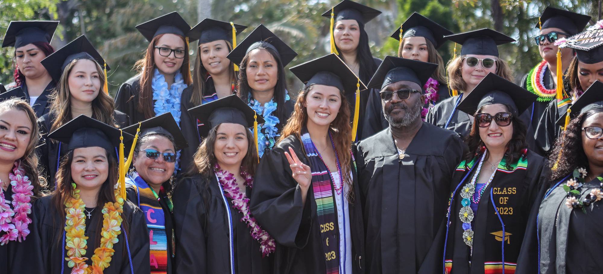 Commencement A group of students in black graduation caps and gowns. Some are wearing flower leis