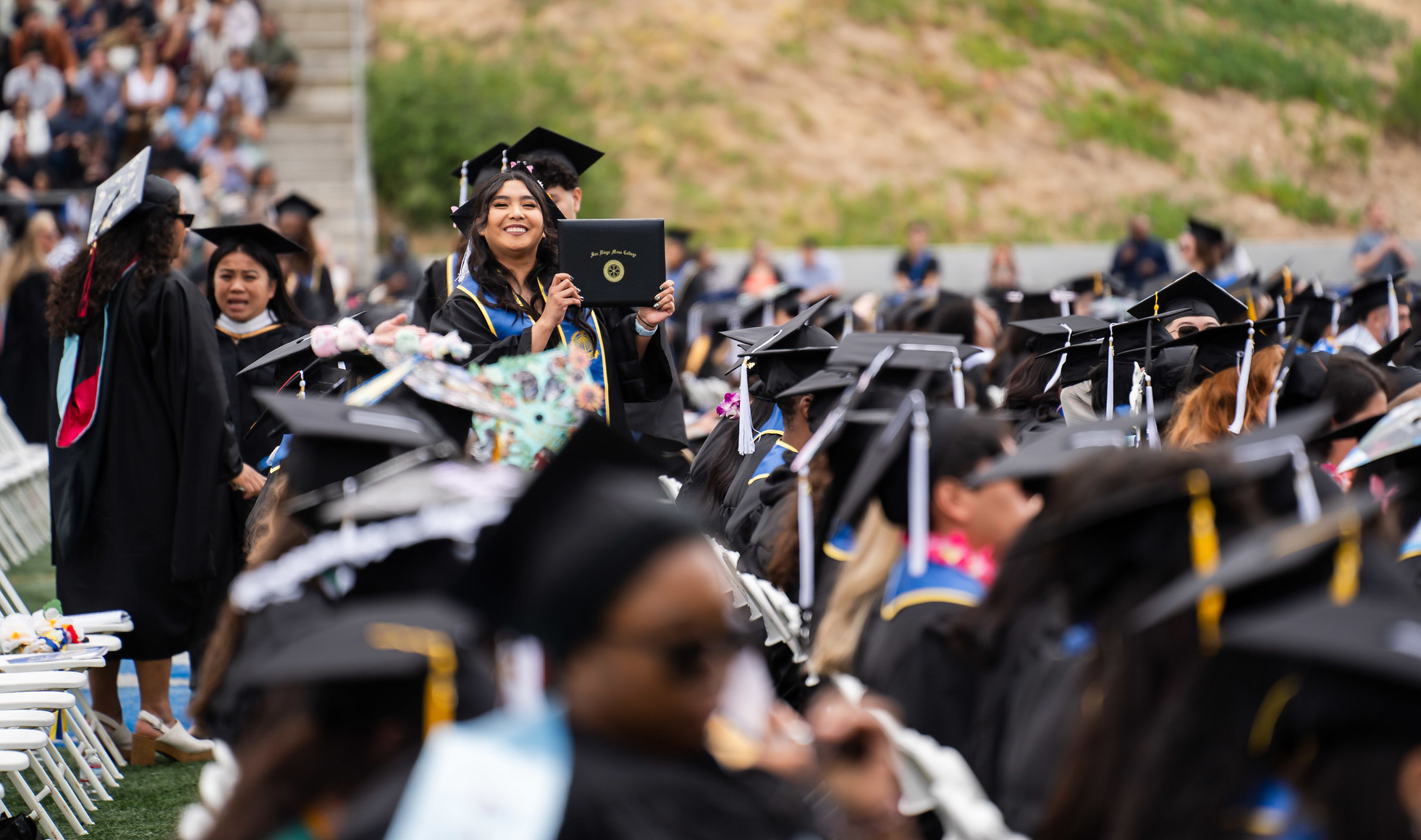 Students in black graduation caps and gowns in their seats at commencement