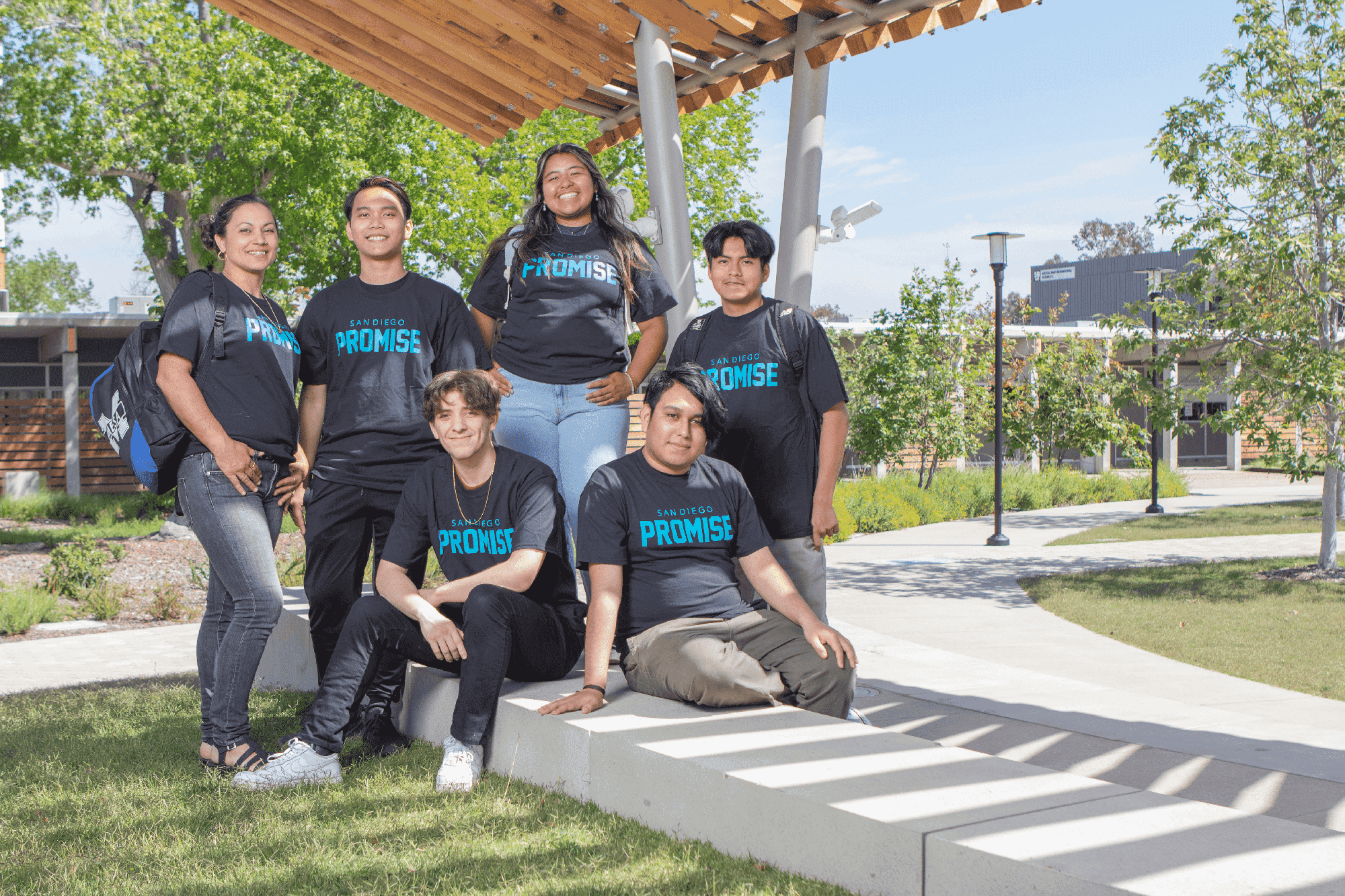 Six students are all wearing black tee shirts with the word promise on them. They are outside in the mesa quad