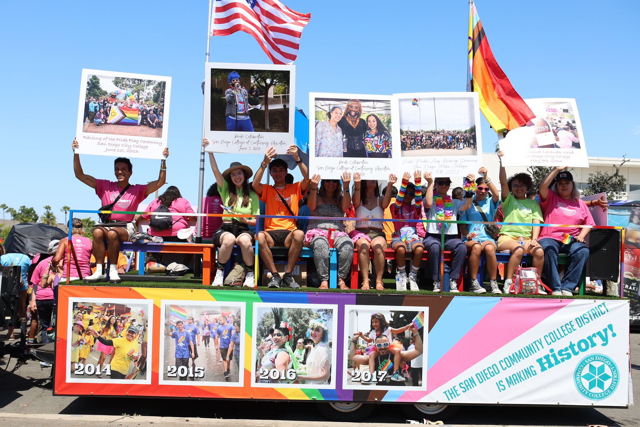 People surround the Pride Parade Float. The float has a pictures all around of students and past pride parades