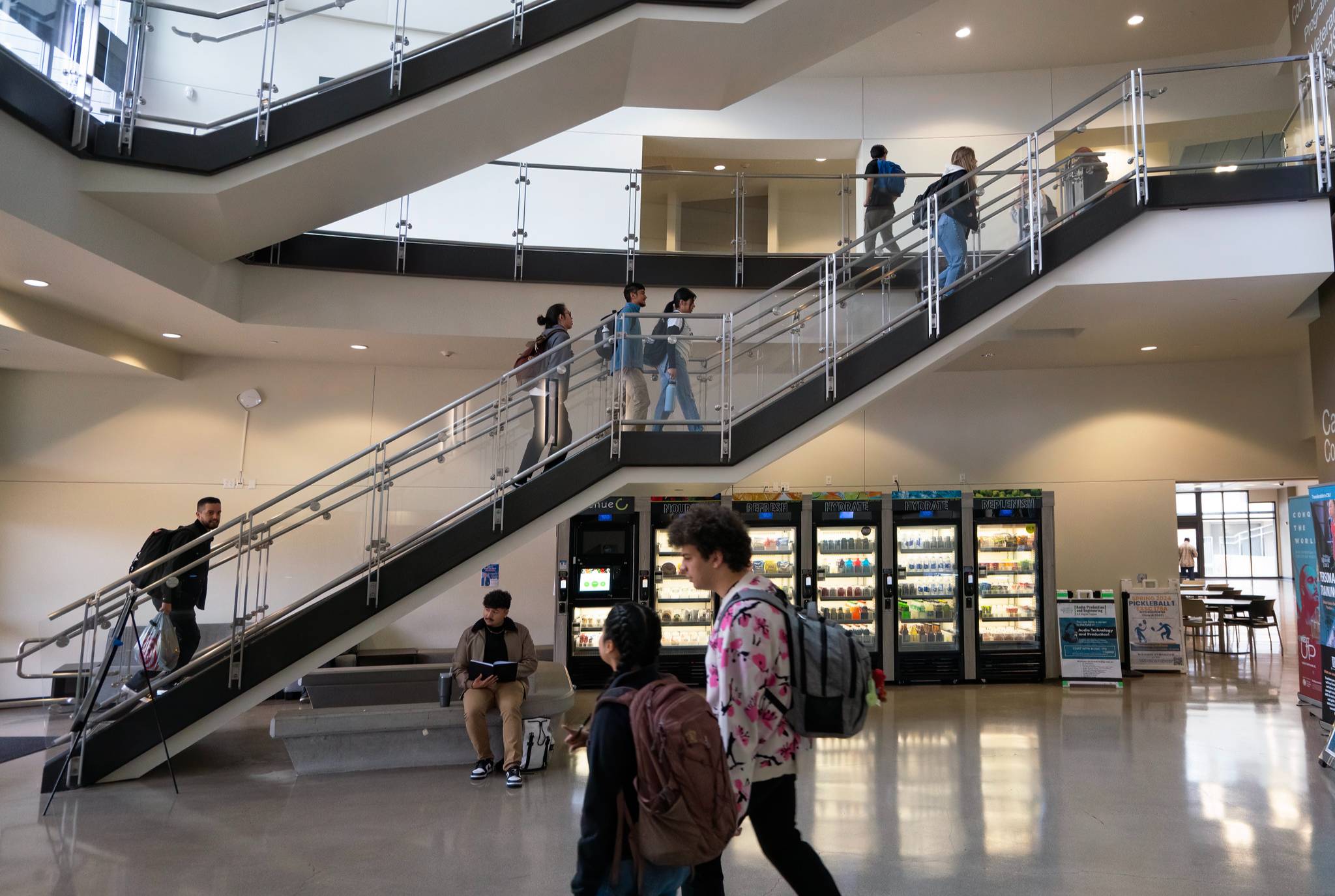 Students walk past a staircase in a campus building.