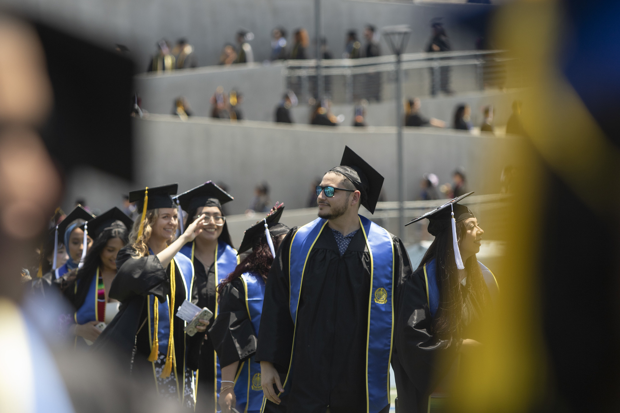 A student in a black graduation cap and gown wearing a colorful stole