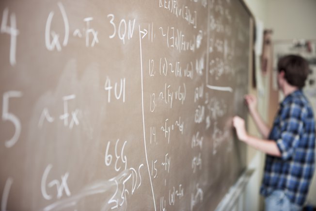 A student writing math problems on a chalkboard