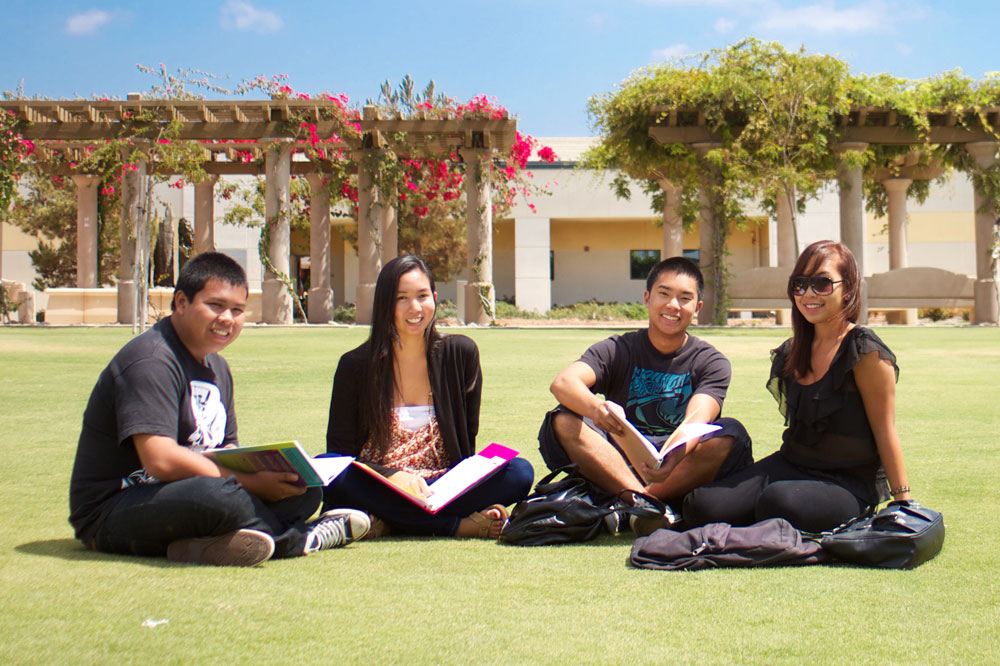 four students sitting on the lawn