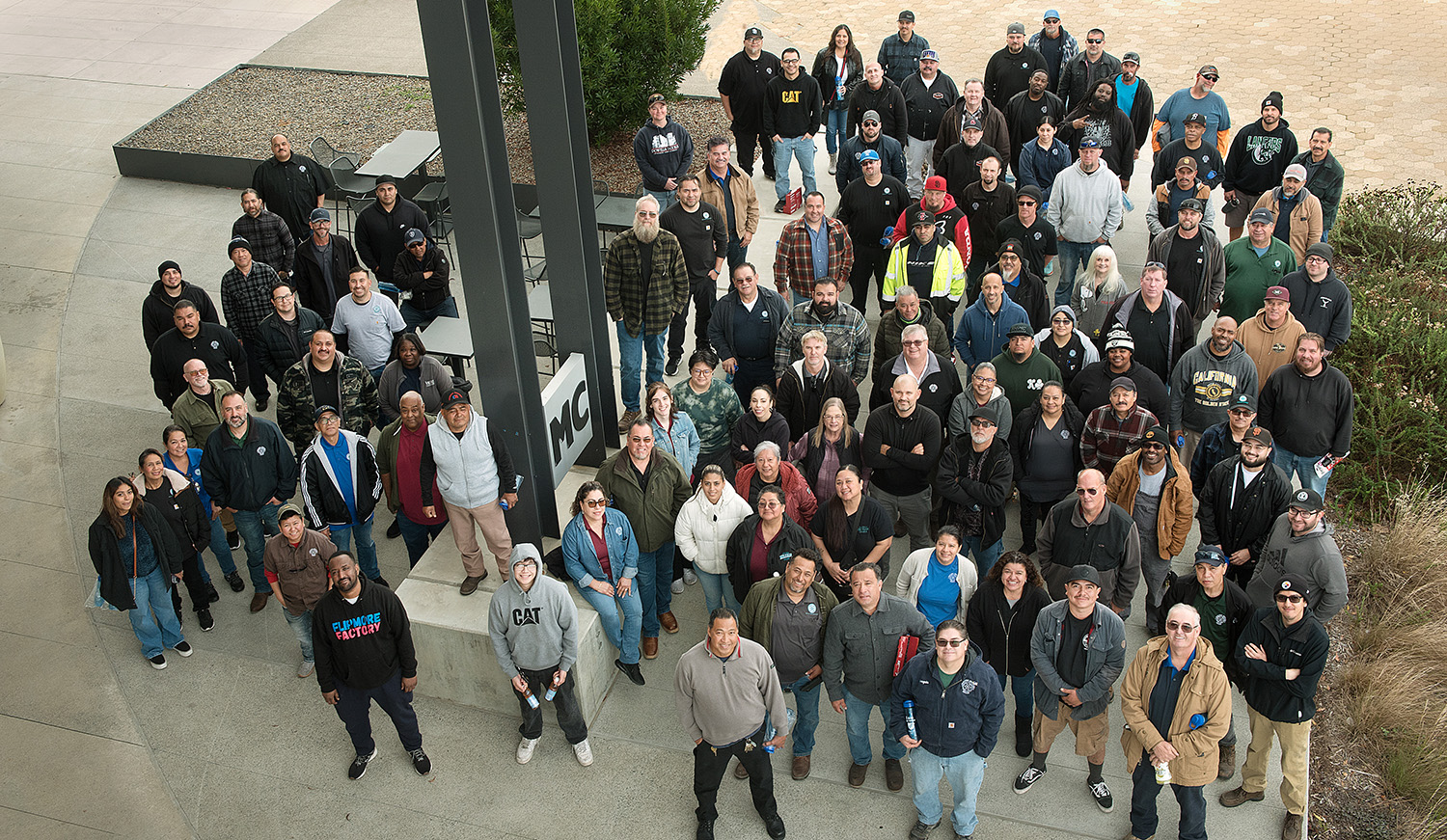 About 70 facilities employees are gathered together and looking up for a group picture.