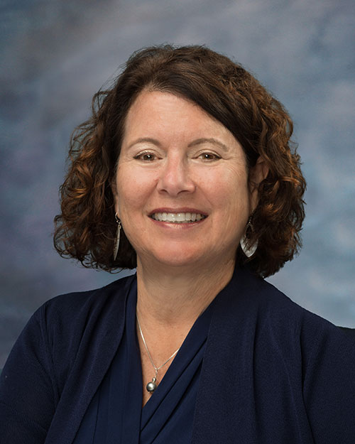 Laurie Coskey is wearing a dark blue top in a business portrait photo