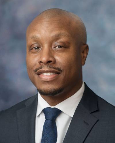 Jared Burns is wearing a gray suit and a blue tie