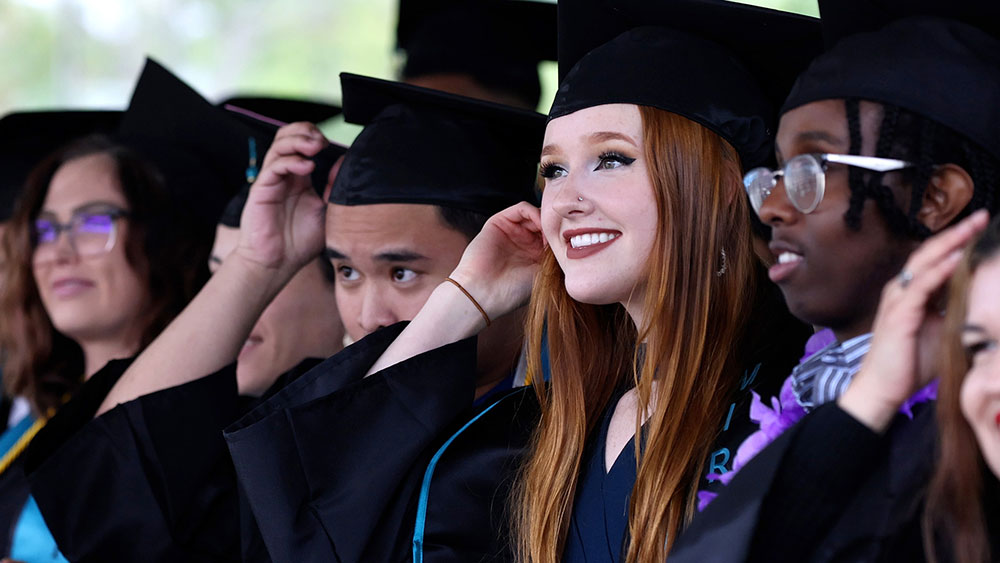 Students at commencement turn the tassels on their graduation caps