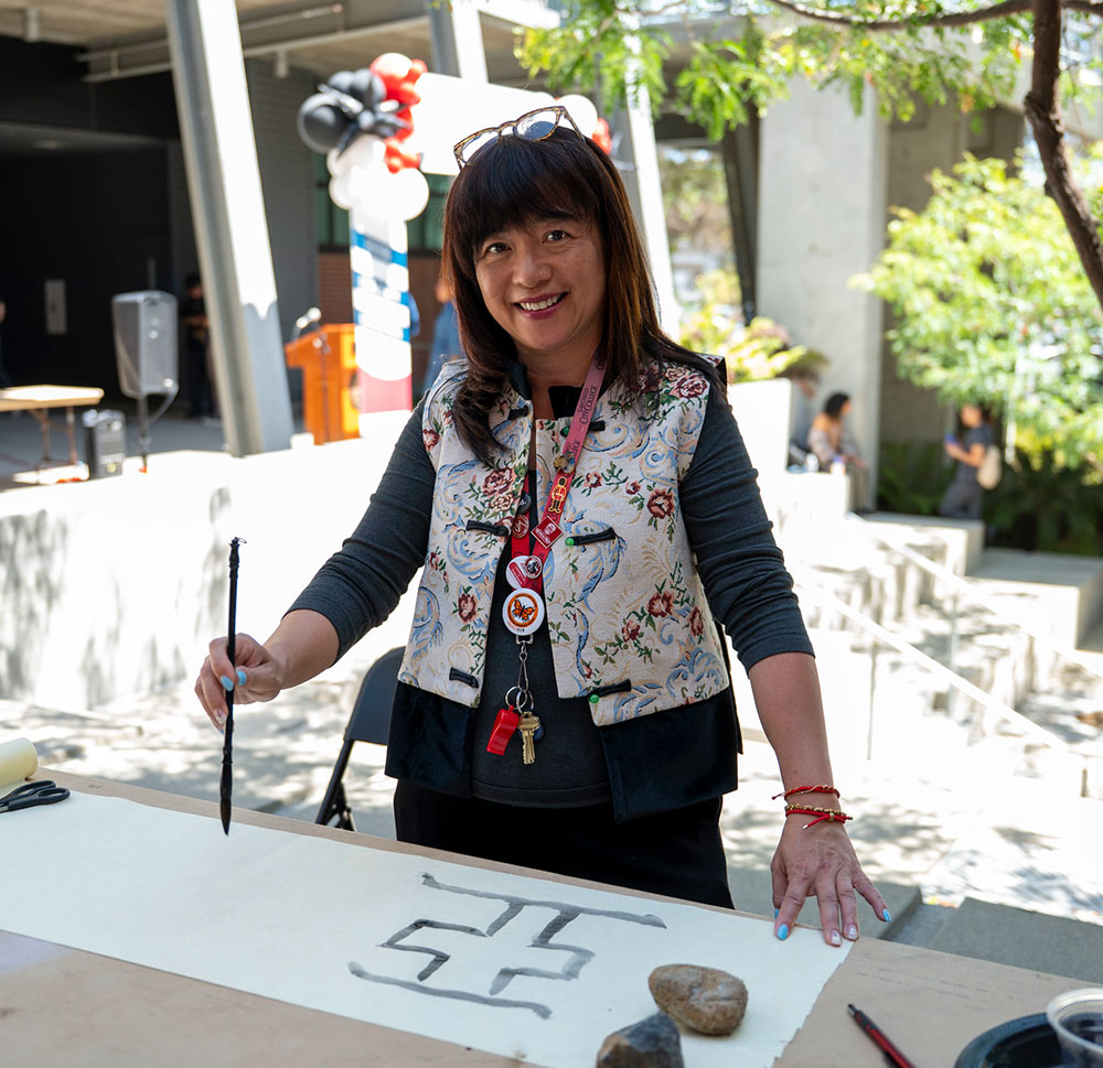A woman painting outside of City College's AANHPI Connections space