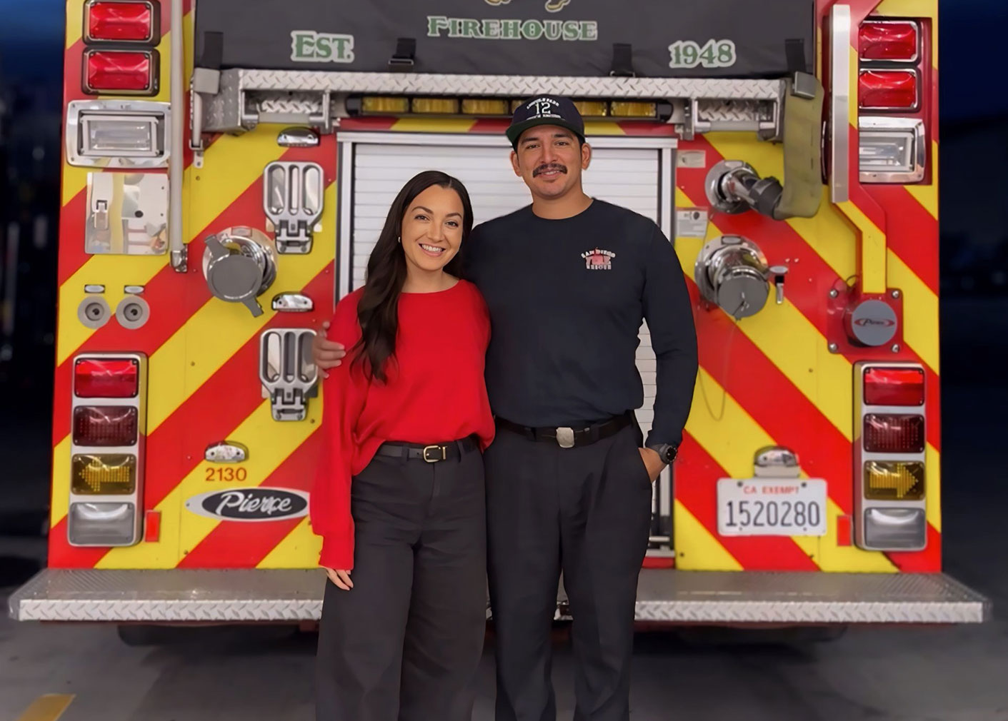 Ulizes Sanchez and a woman stand at the back of a fire truck