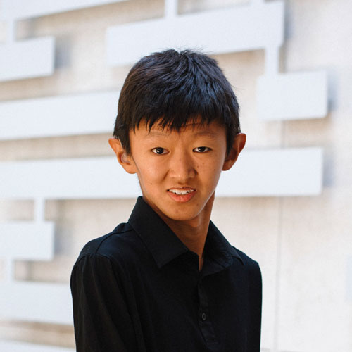 SDCCD student is smiling, wearing a black shirt against a geometric patterned background.