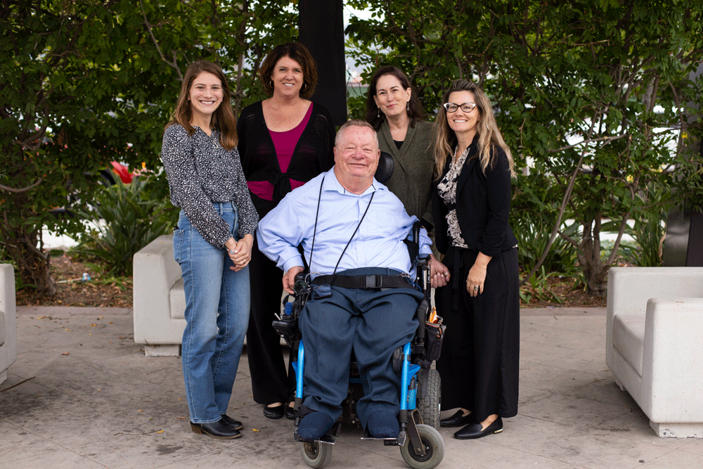 Five employees outside in front of greenery.