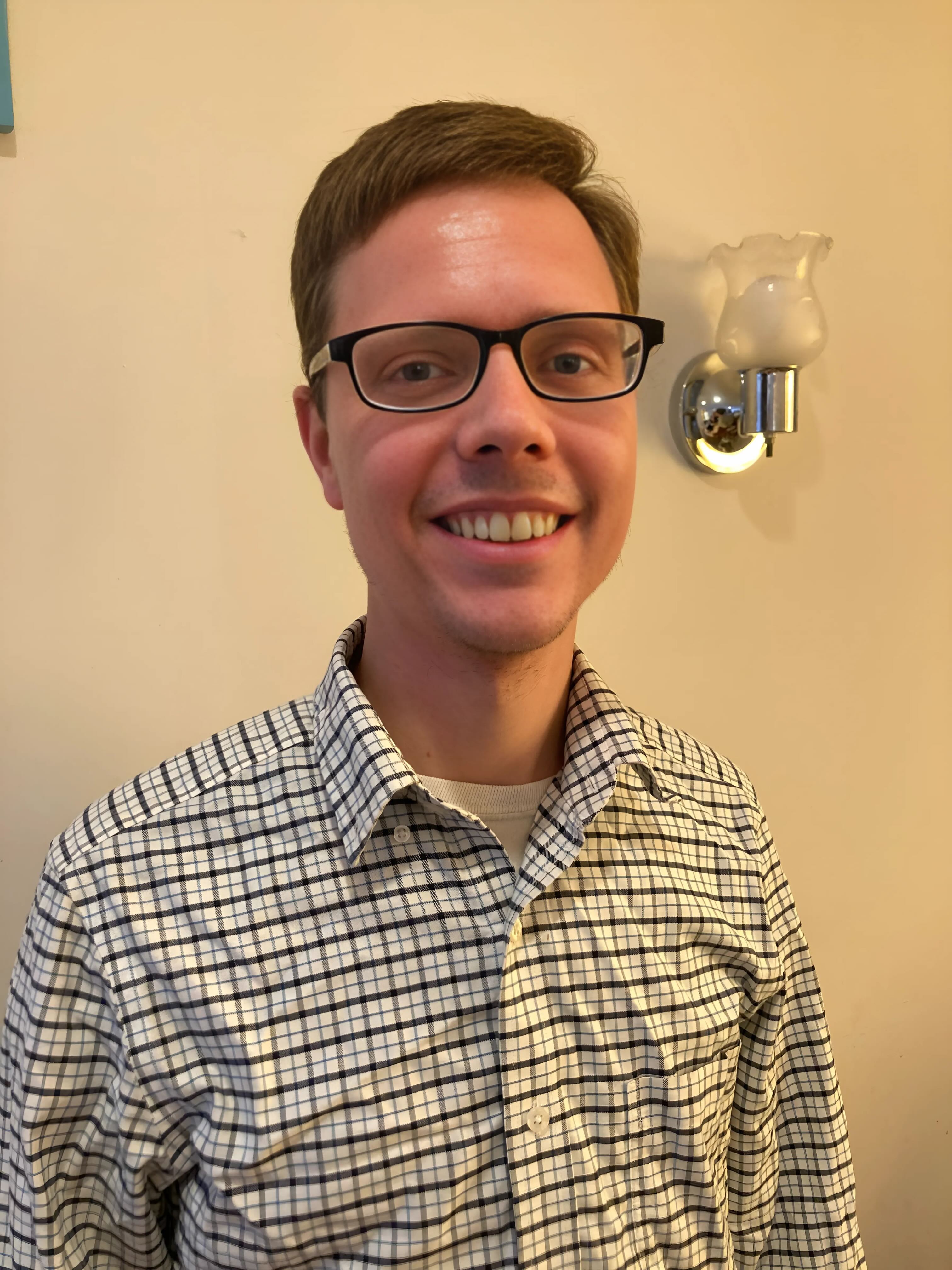 Jason Gulya standing with buttonup shirt smiling