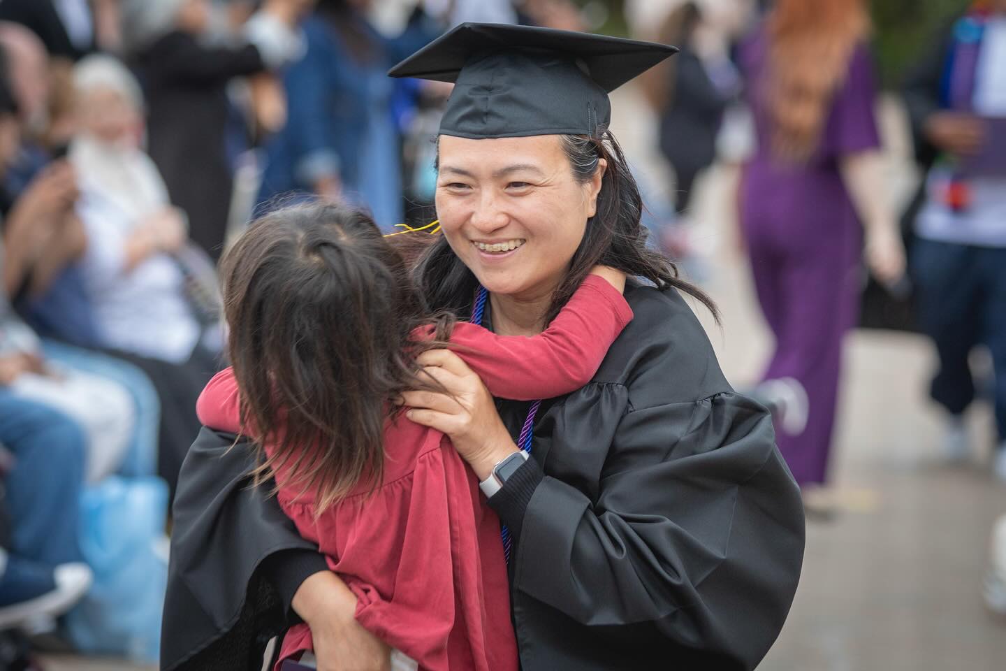 
A graduate hugs a child.
