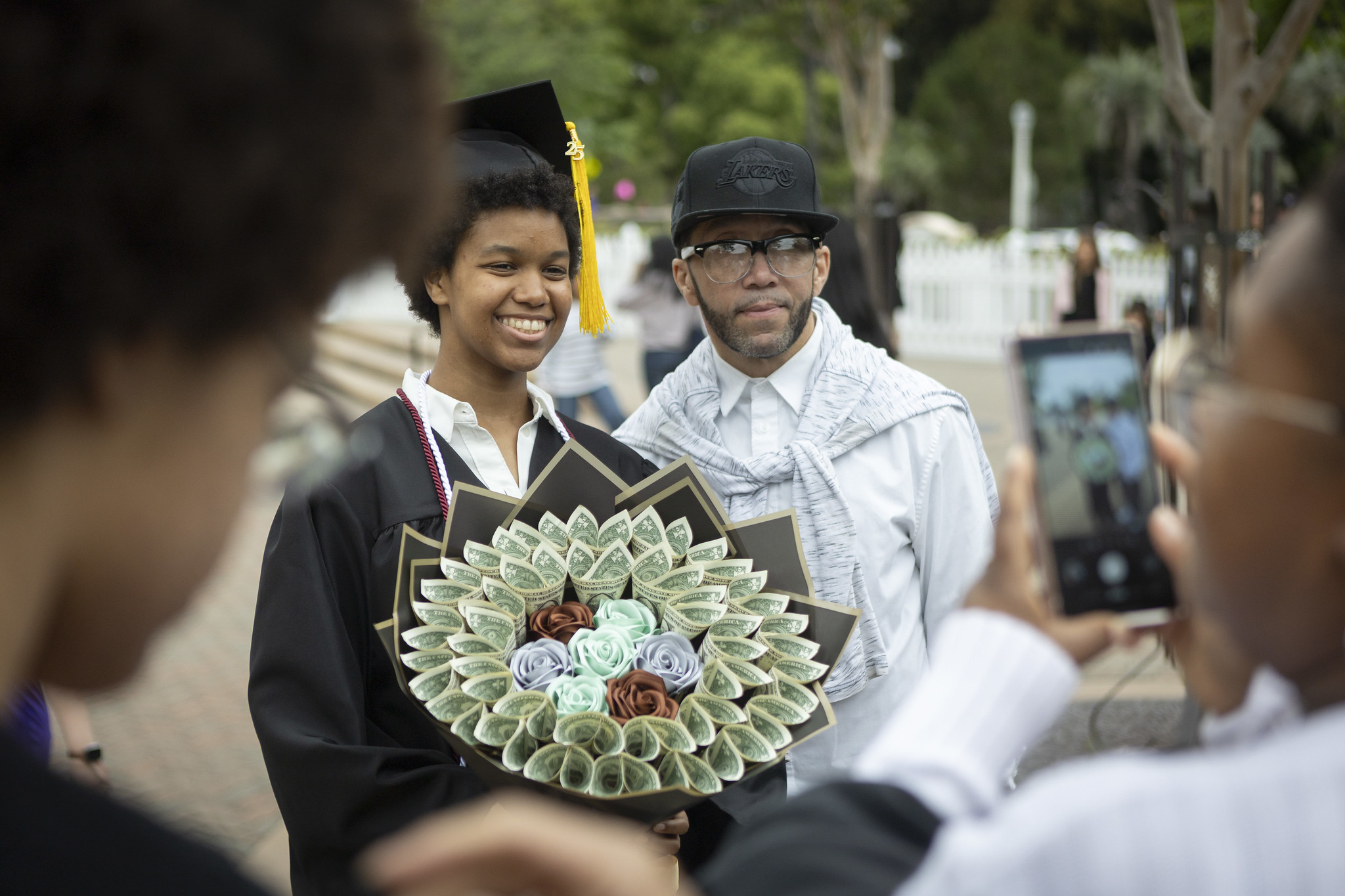 
A graduate with a loved one has his picture taken with a bouquet of one dollar bills.
