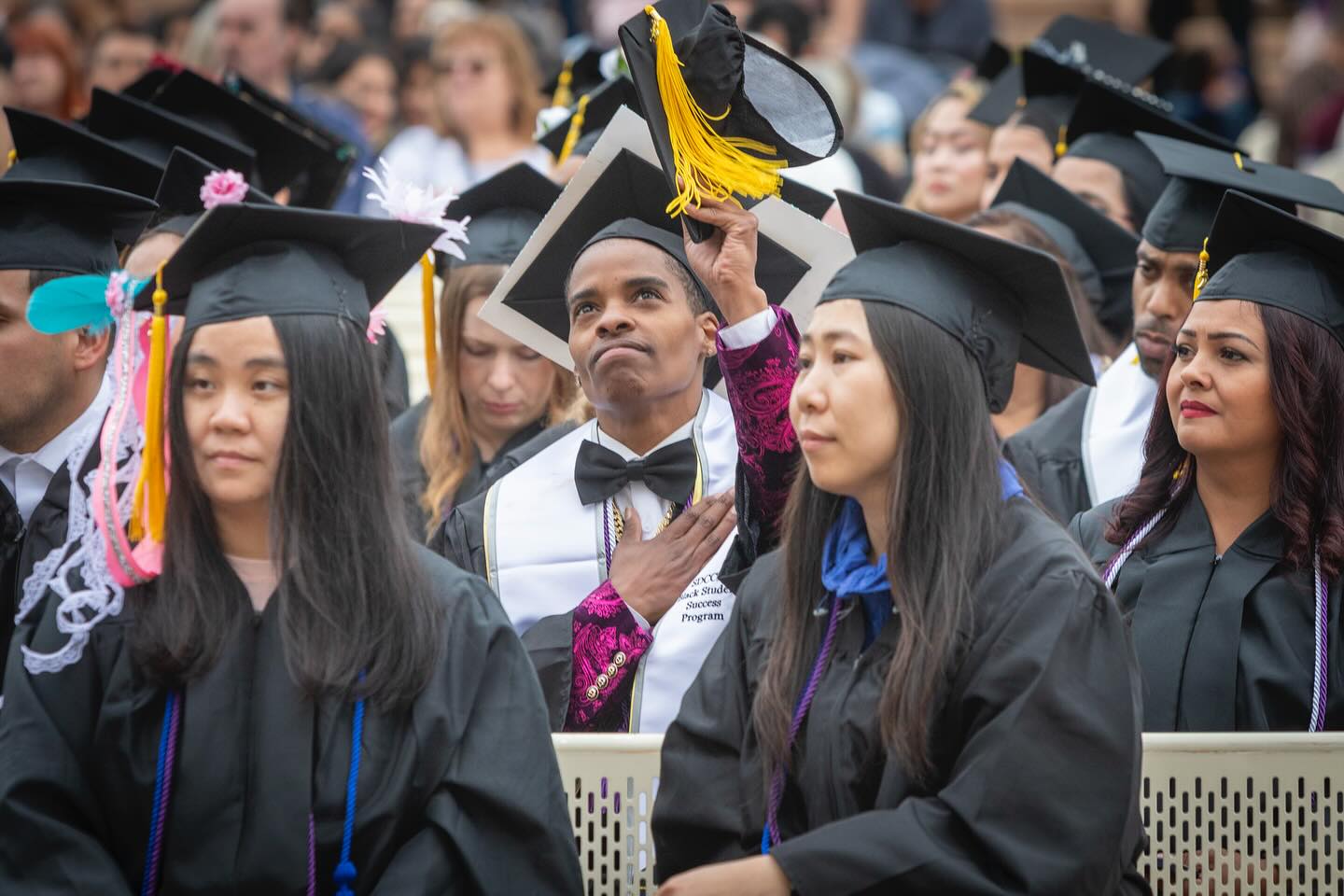 
A graduate in the audience points to the sky with gratitude.
