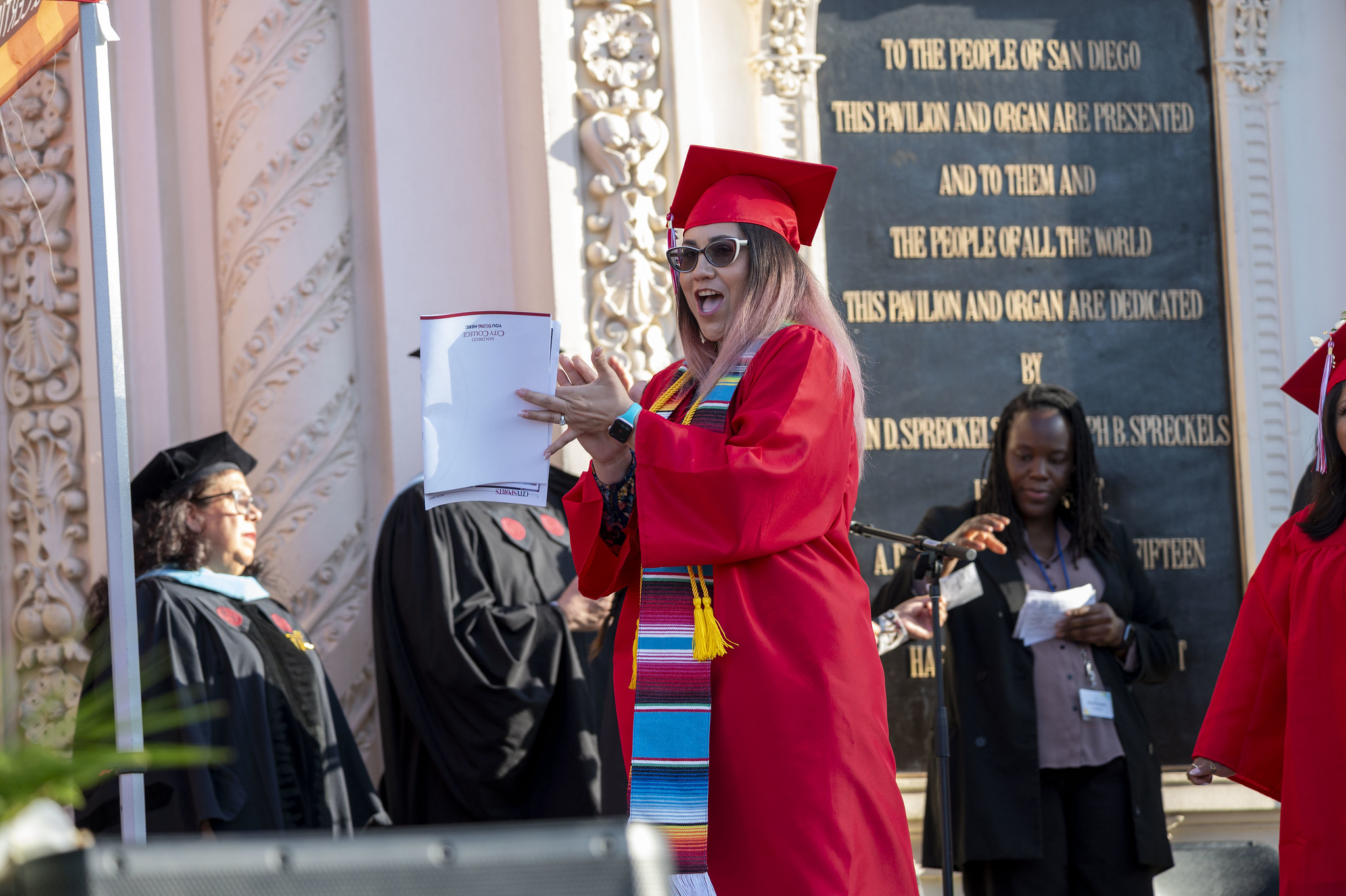 
A graduate applauds on stage.
