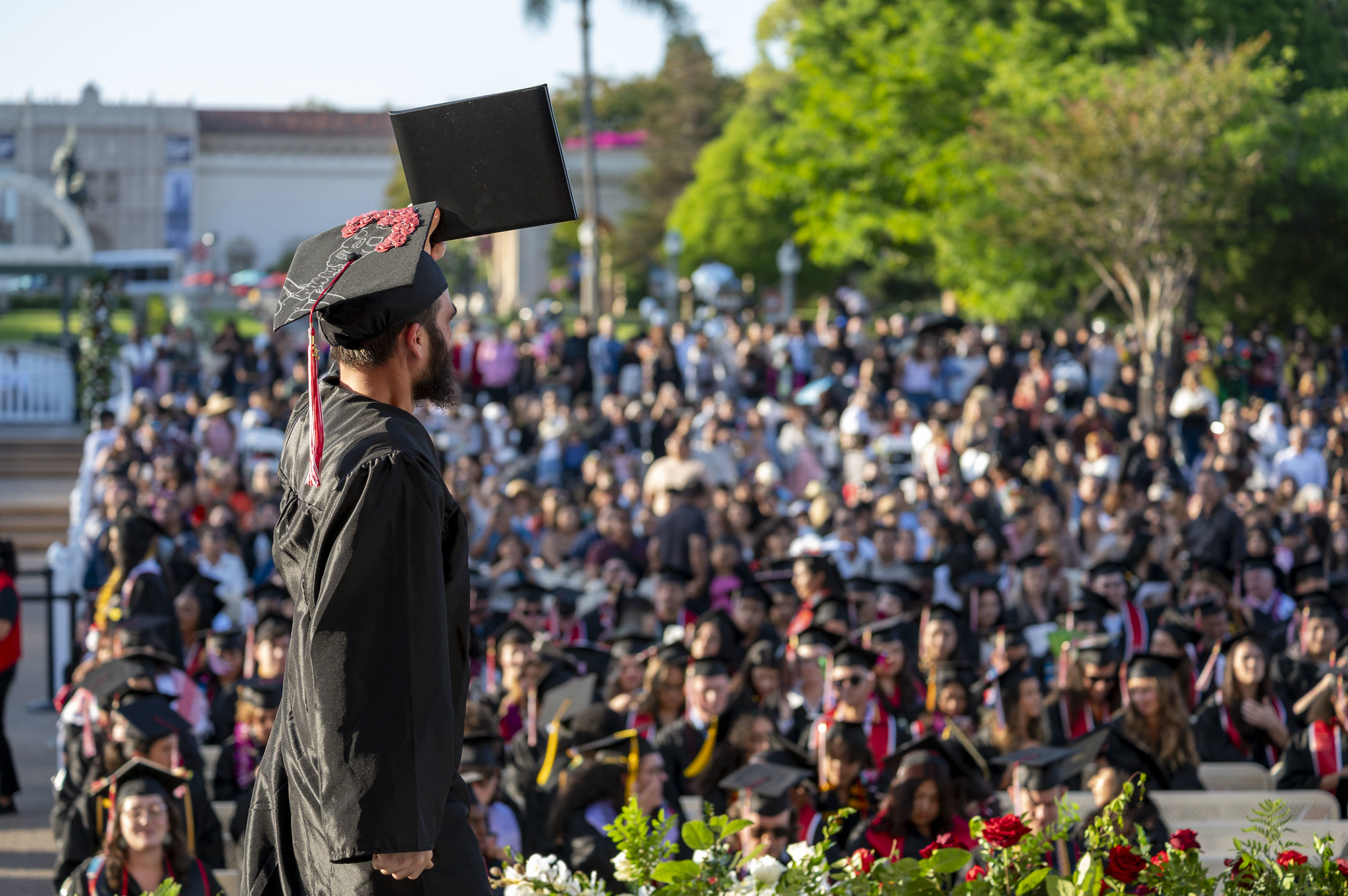 
A graduate holds up his degree to the audience as he walks across the stage.
