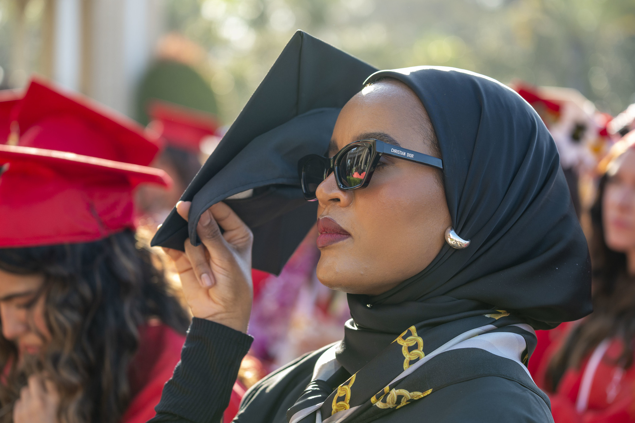 
A graduate uses her cap to shield her eyes from the sun.
