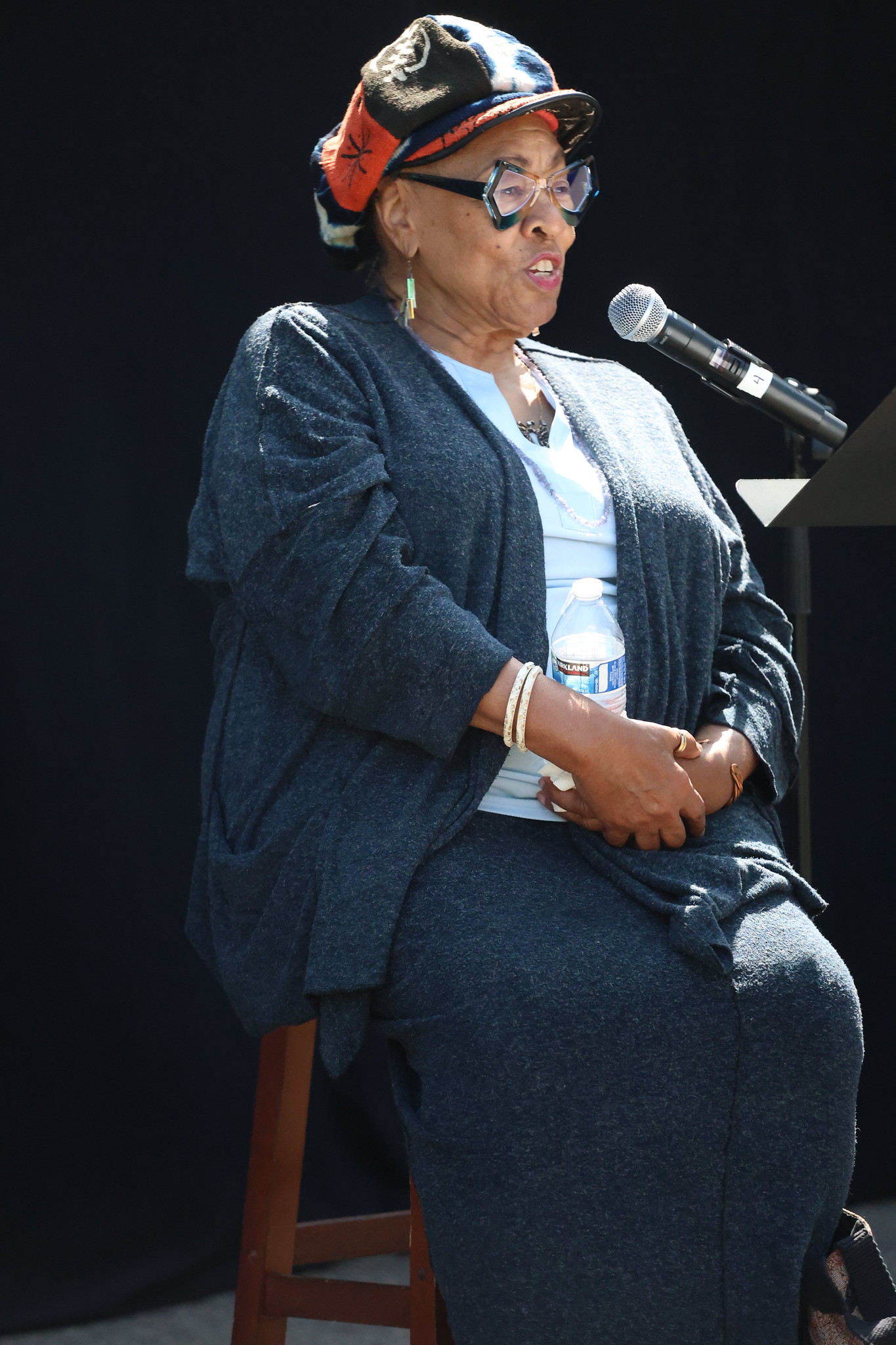 
A woman at a microphone performing poetry.
