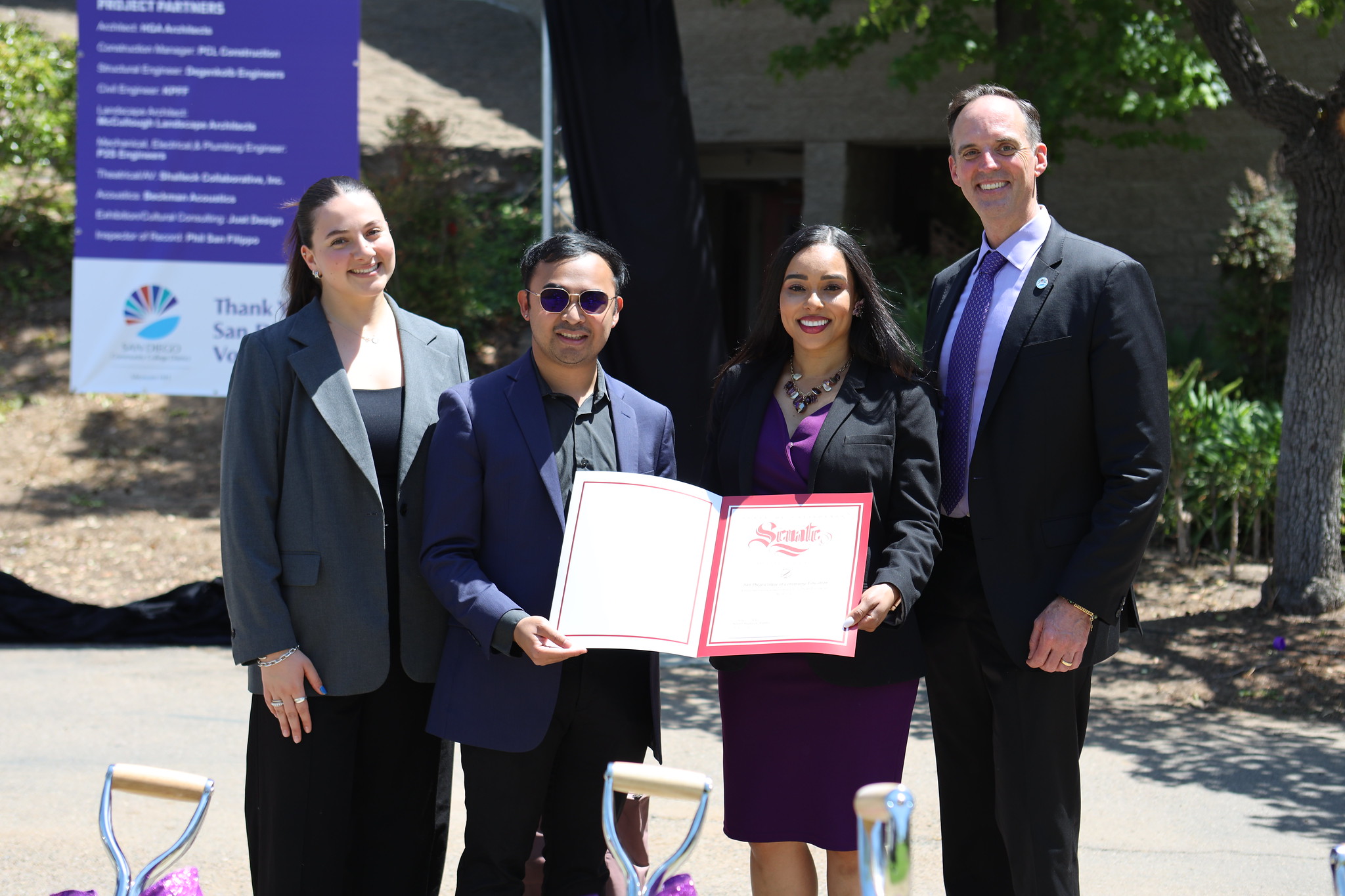 
Four people holding a folder.
