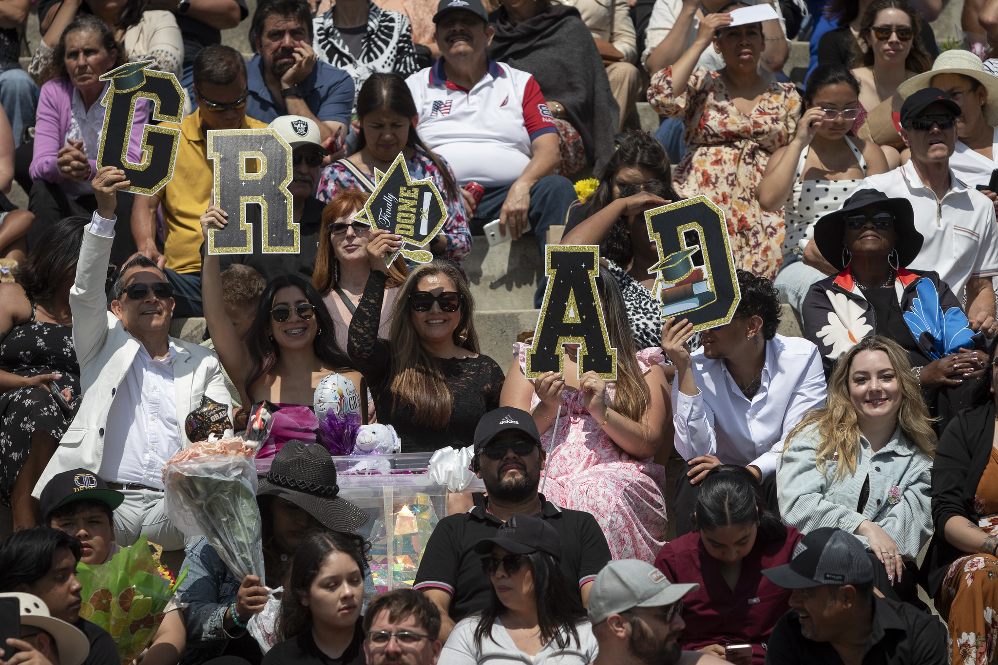 
Members of the audience hold up letters that spell Grad.
