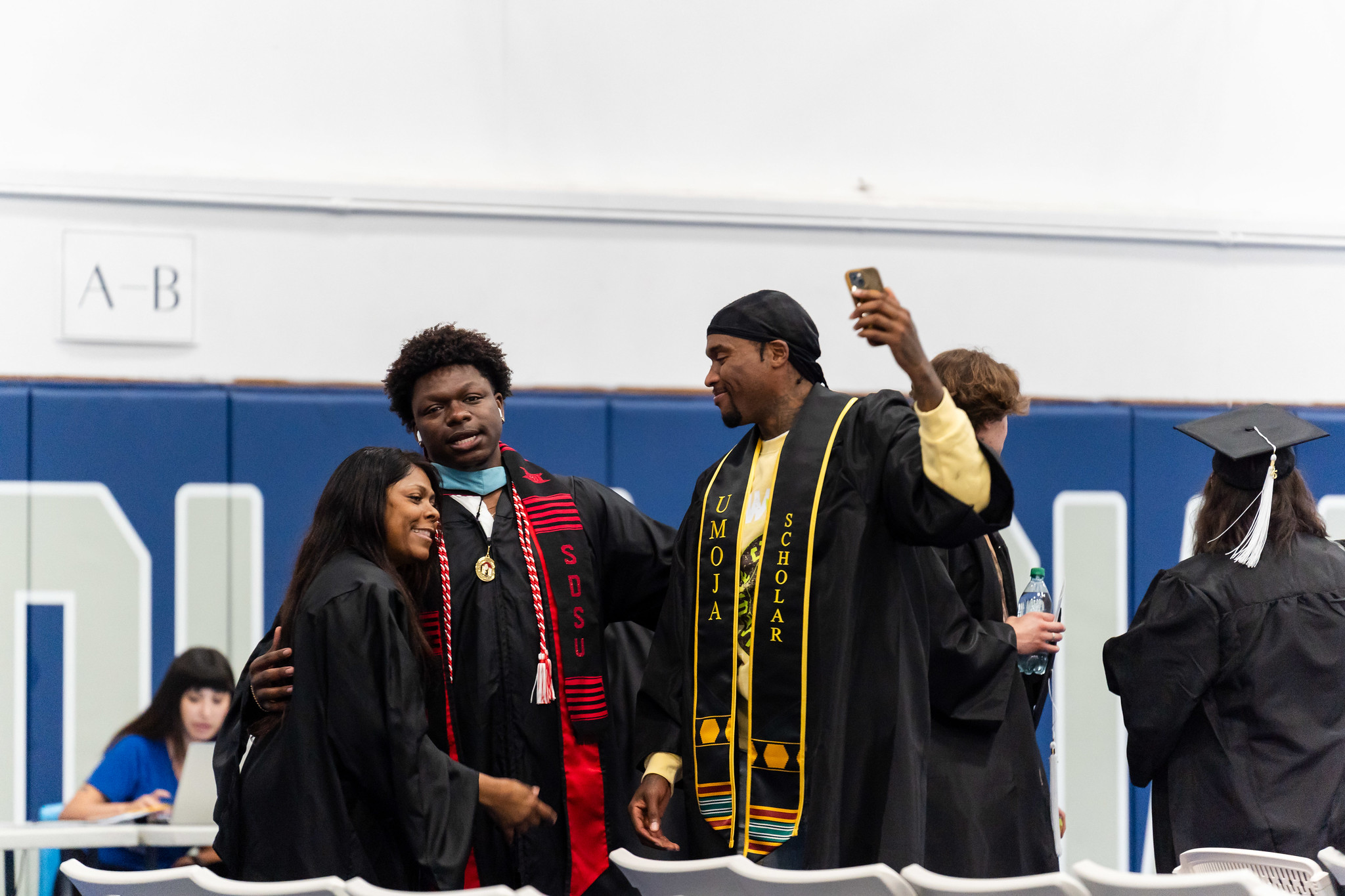 
Three graduates in the gym waiting for commencement to start.
