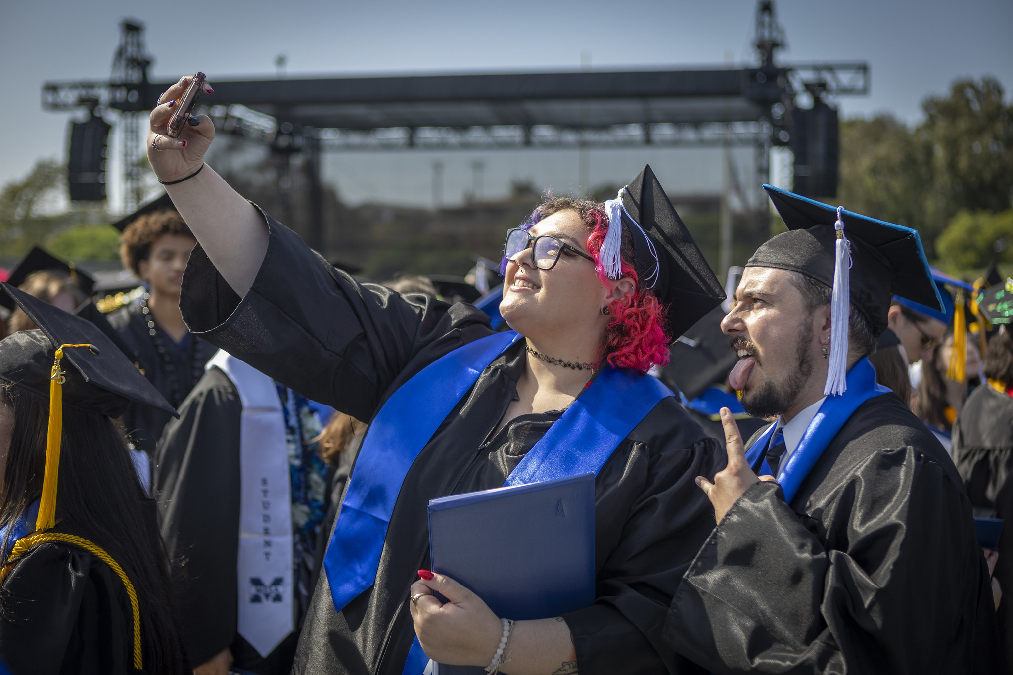 
Two graduates taking a selfie after receiving their degrees.
