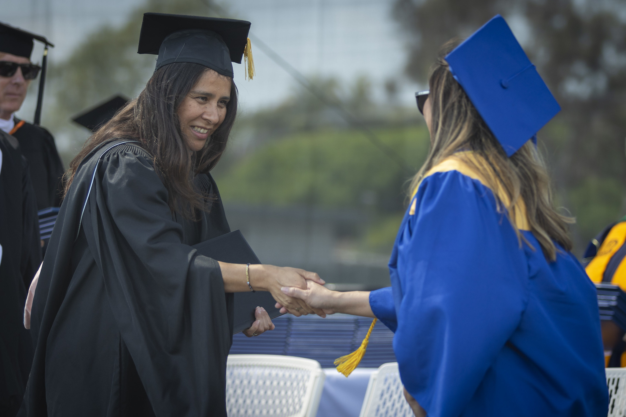 
Trustee Geysil Arroyo hands a graduate a diploma.
