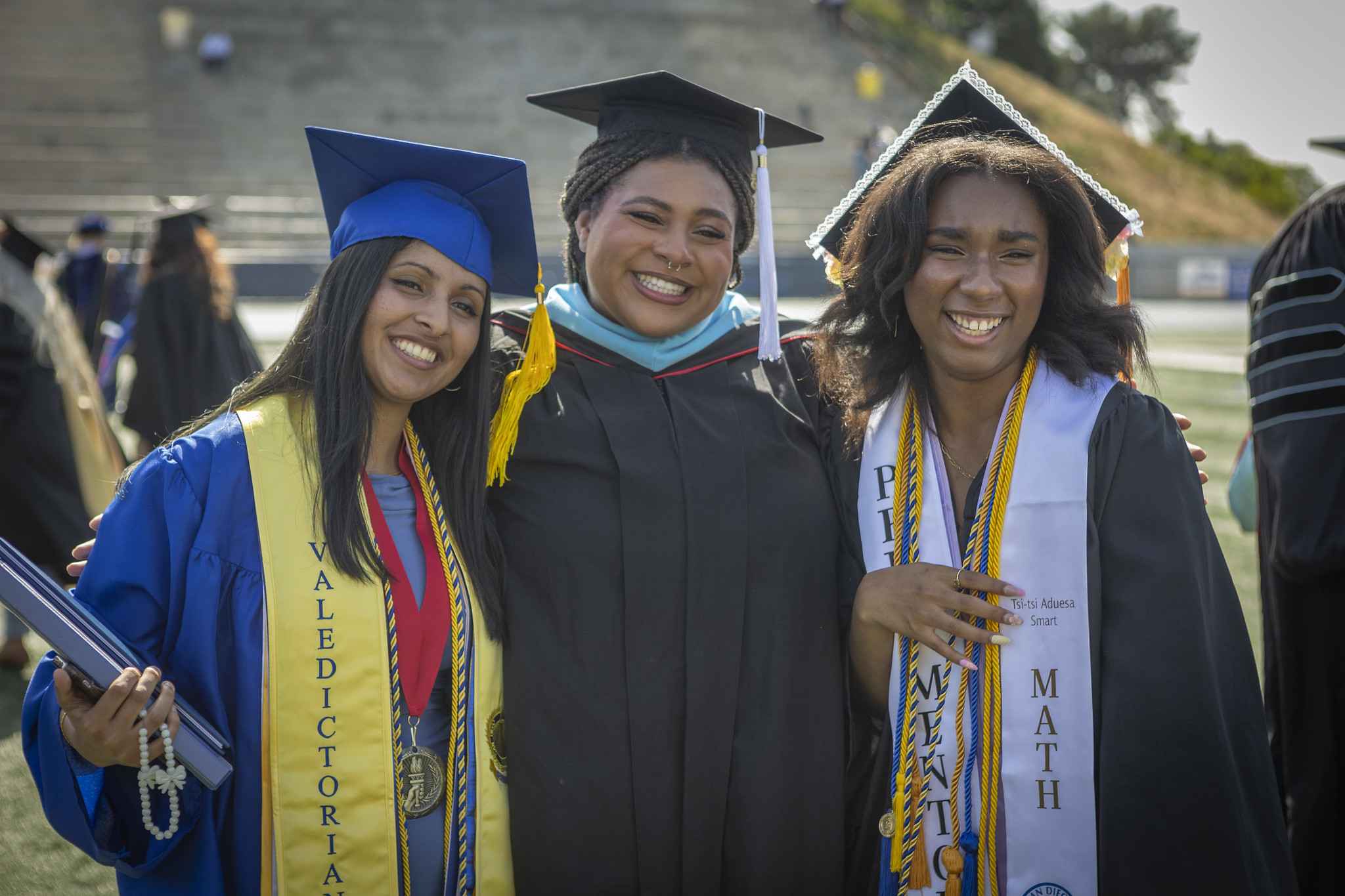 
Three graduates hug.
