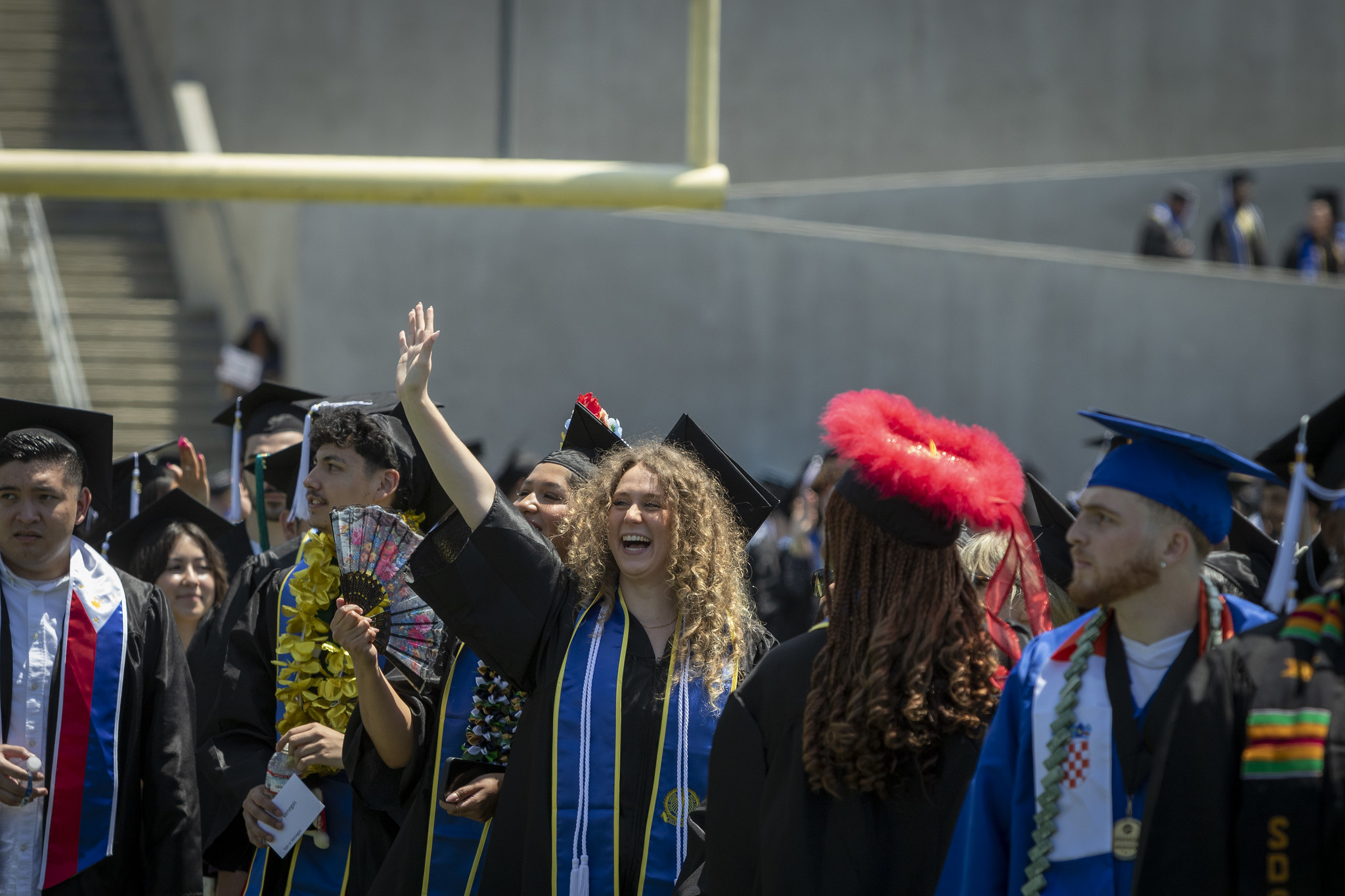
A graduate in a crowd waves at the audience.
