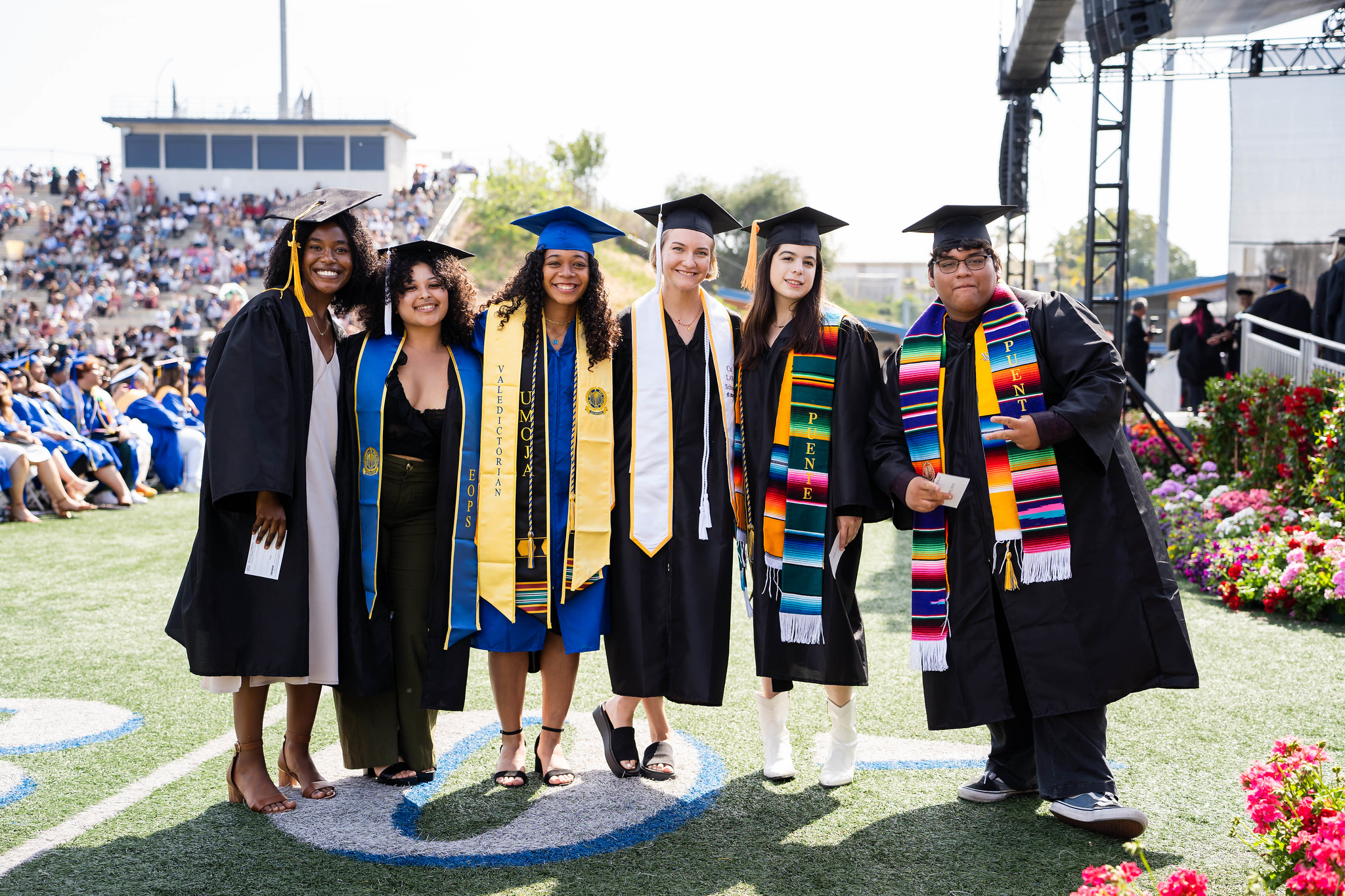 
Six graduates line up for a group photo on the field at commencement.
