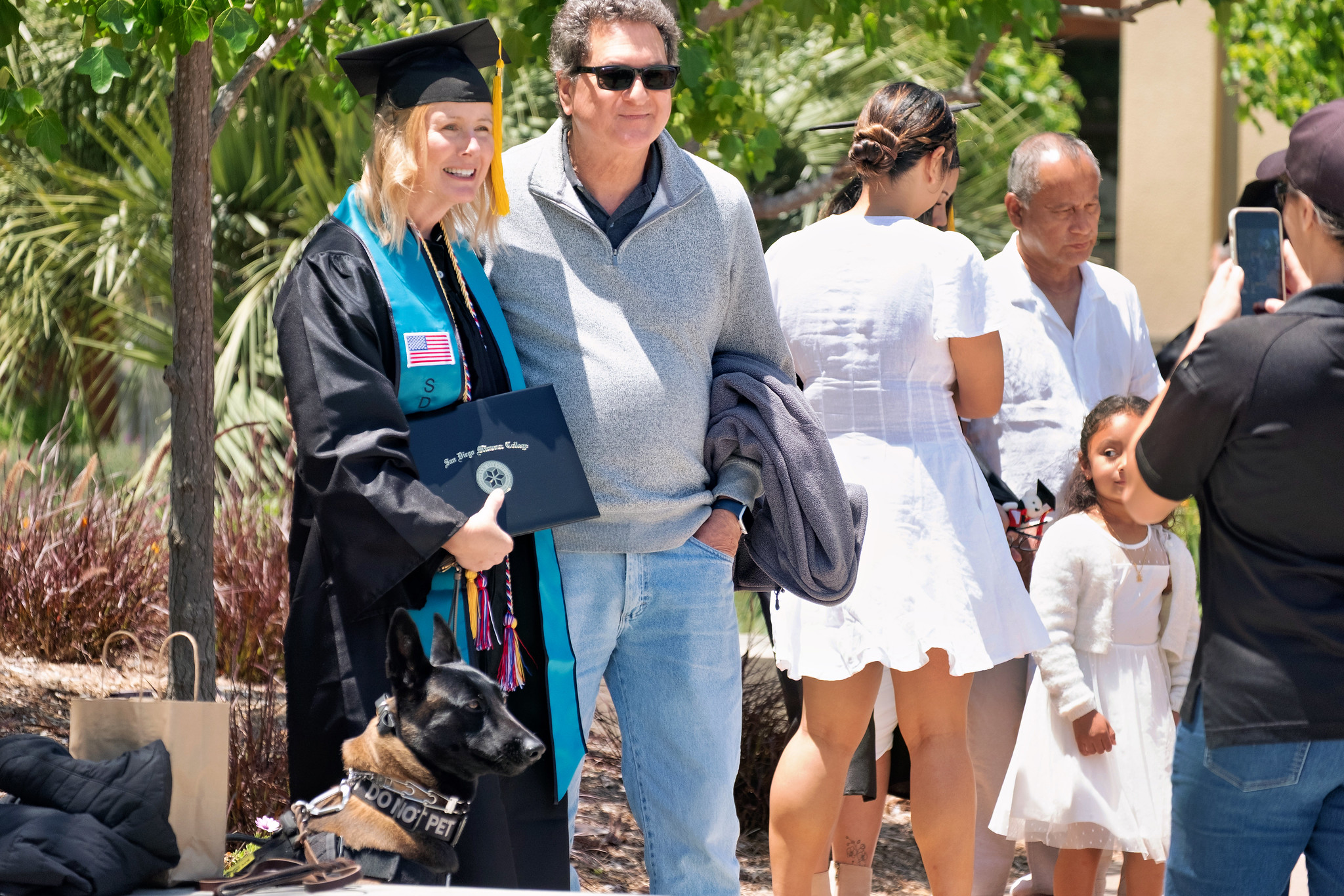 
A graduate with a support canine takes pictures with her family.
