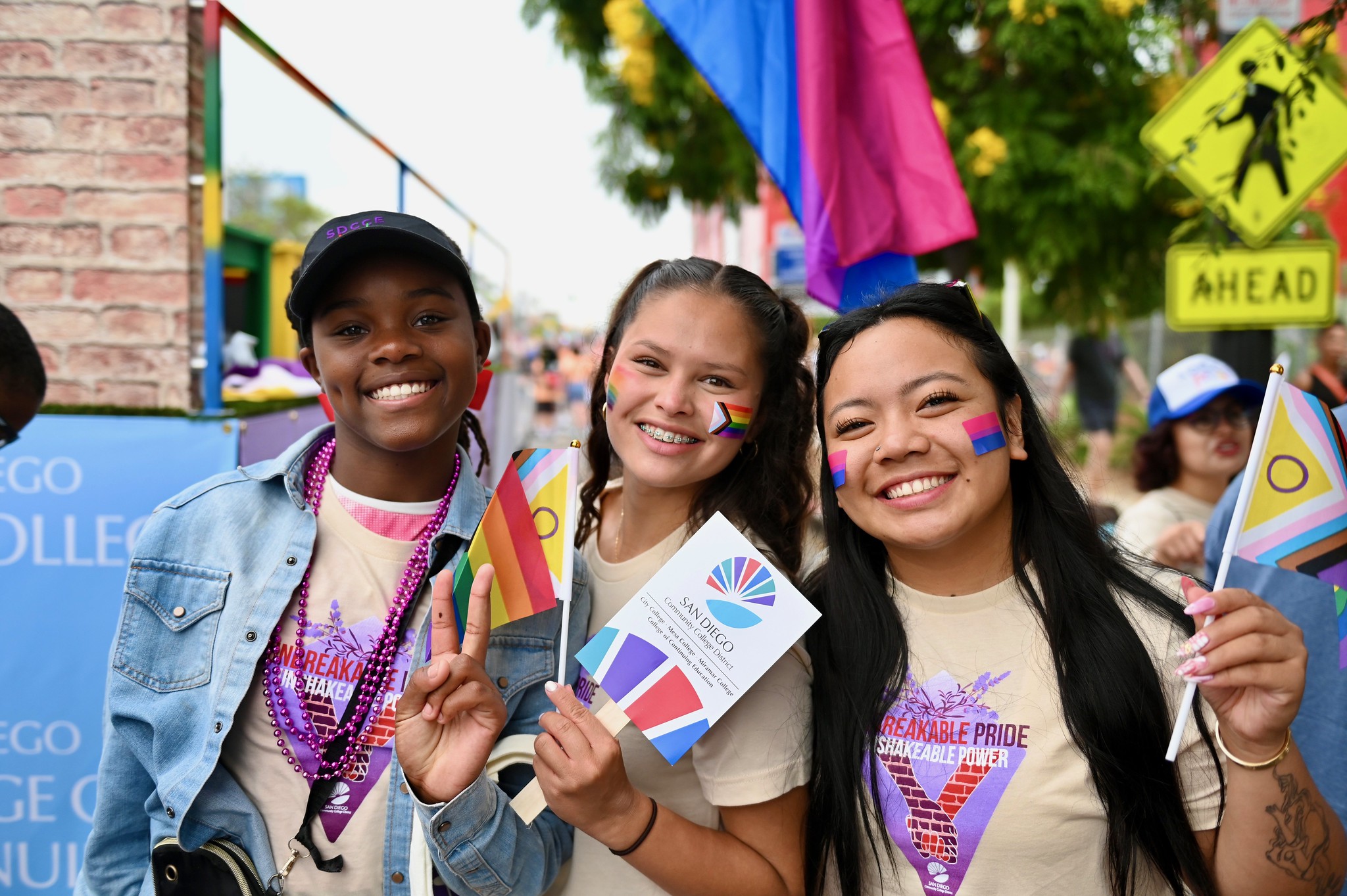 
Three girls with temporary rainbow face tattoos smiling before the start of the San Diego Pride Parade.
