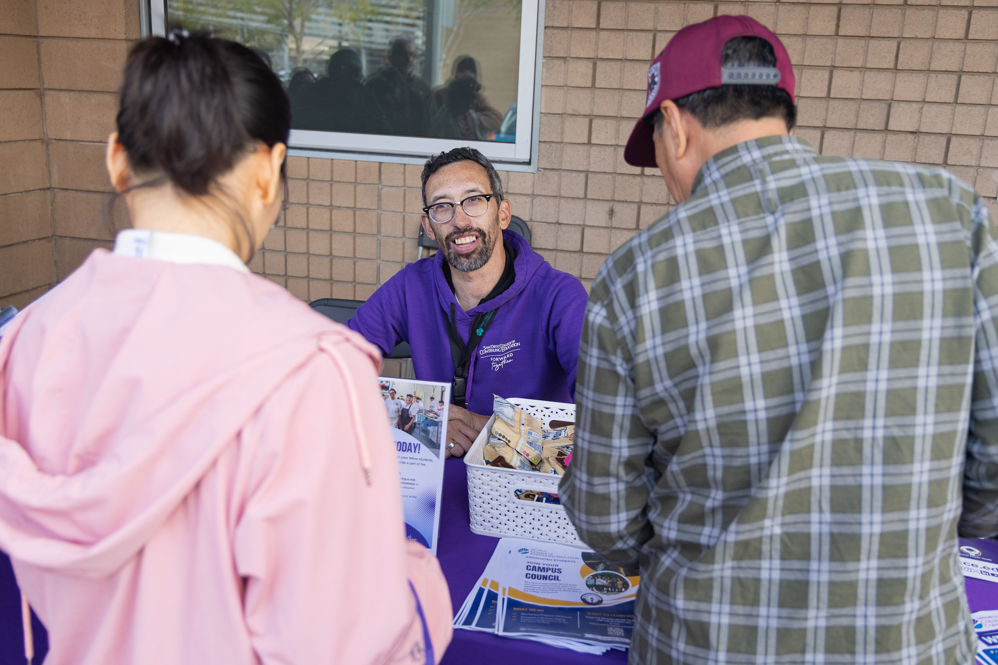 
Employee Neill Kovrig speaks to two people a Continuing Education welcome table.

