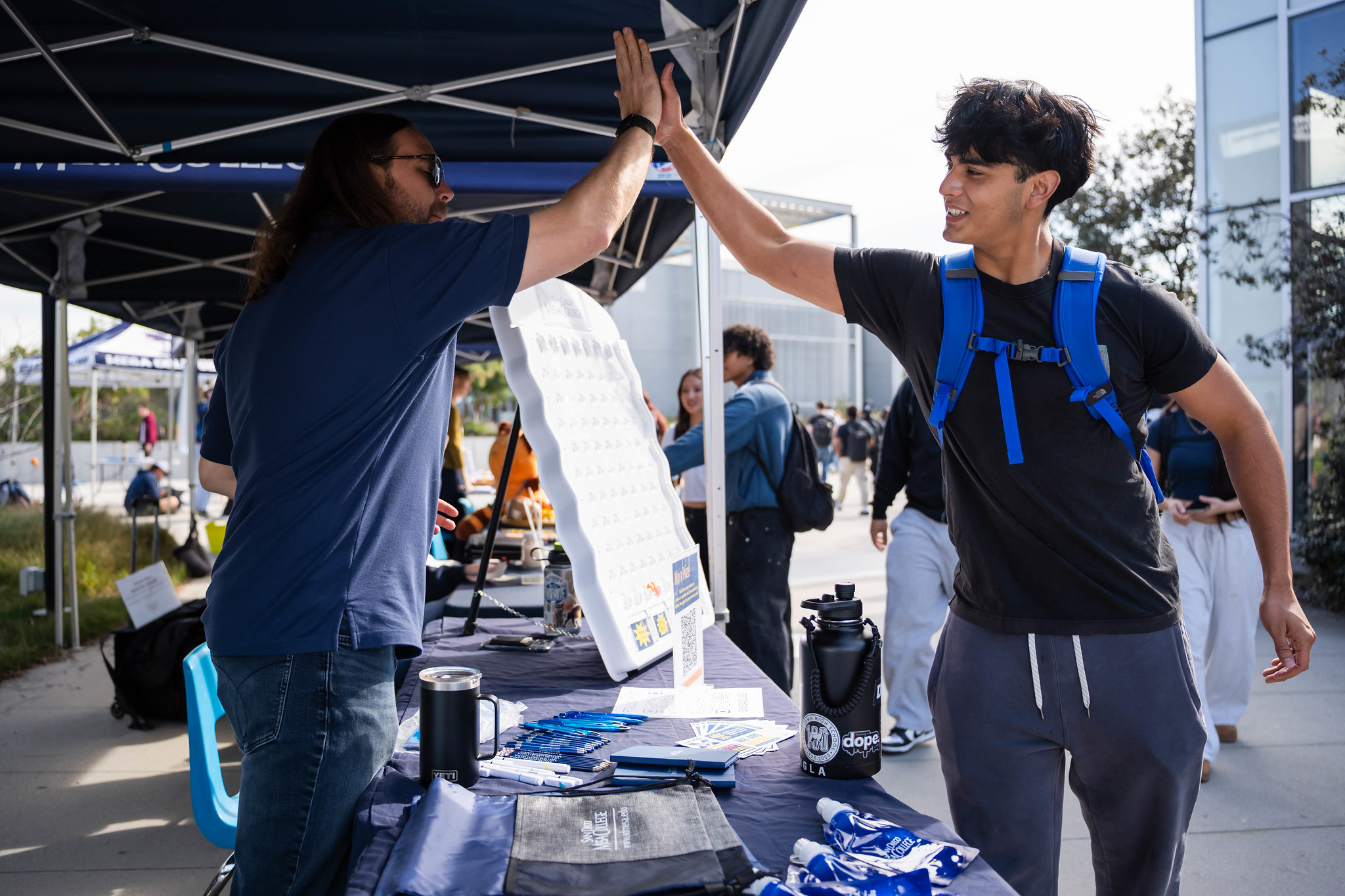 
A student high-fives a worker at a Mesa College welcome booth.
